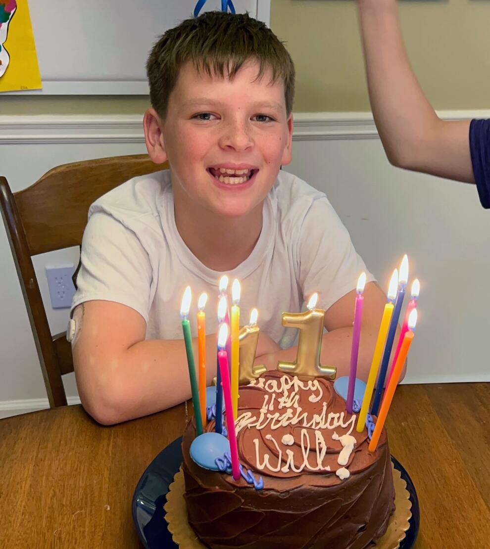 Will, age 11, sits with a birthday cake.