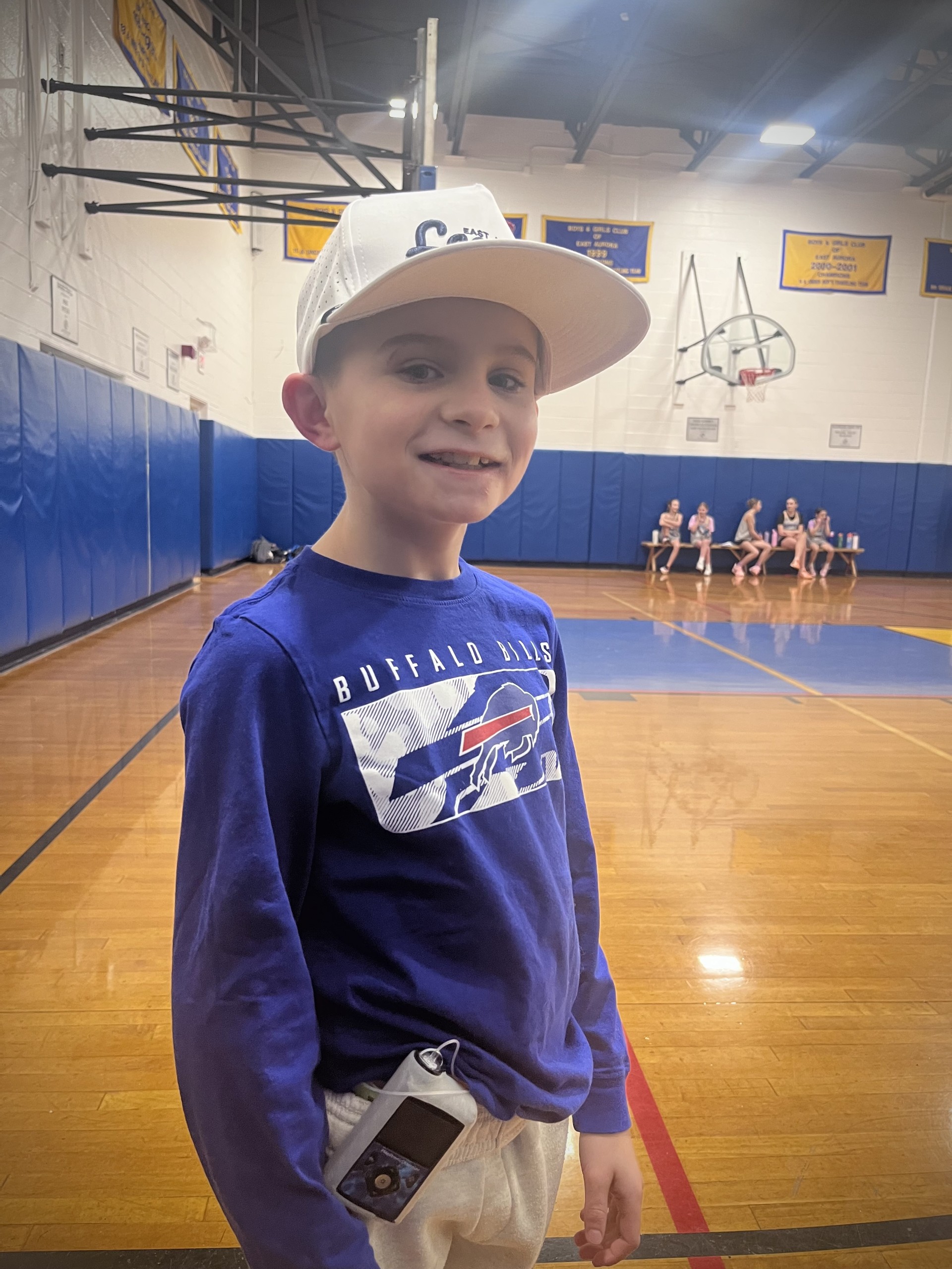 Brett on a basketball court, showing off his insulin pump