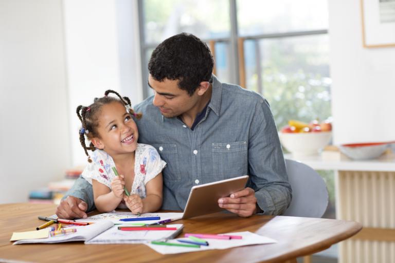 A little girl and her father spend time together coloring.
