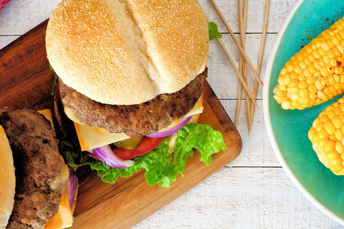 A photo of summer food favorites, hamburgers and corn on the cob.