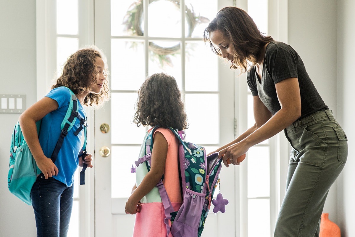 A mom helps her two daughters get ready for school.