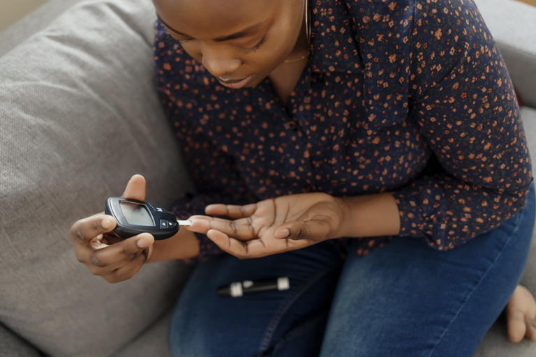Young woman uses a glucometer to check her blood sugar