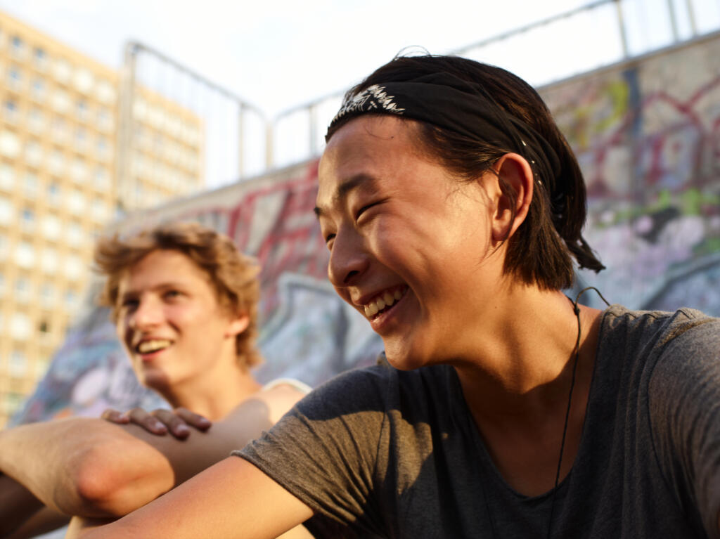 Dos jóvenes adultos sentados fuera riendo