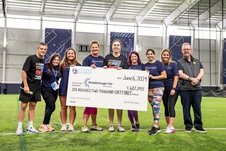 Adam Singer, pictured far right, presents the fundraising results of the 2024 Real Estate Games