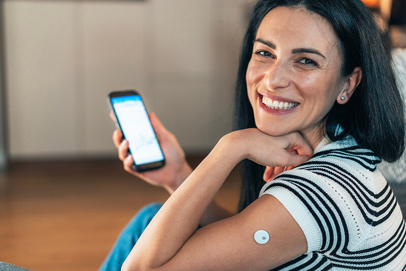 Adult woman checks her blood sugar with a continuous glucose monitor (CGM)