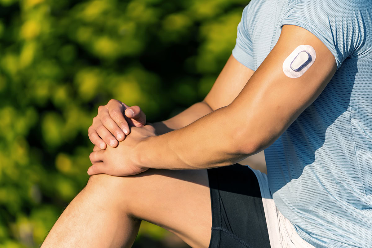 Athlete Stretching with Continuous Glucose Monitor Transmitter Adhered to Arm