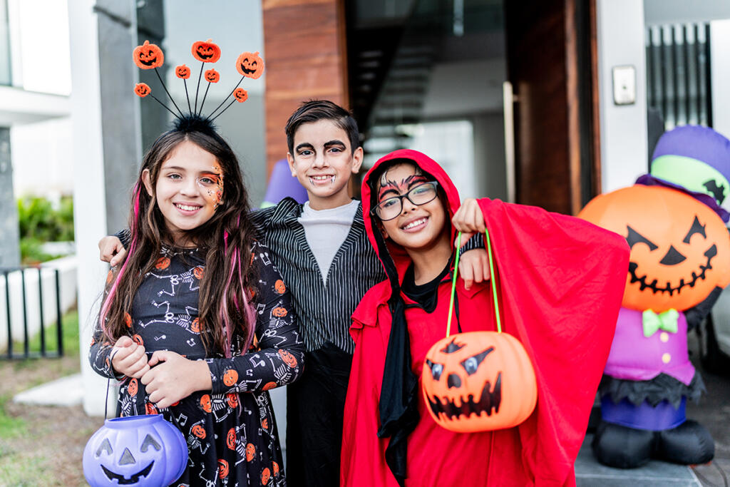 Three children in Halloween costumes go trick or treating