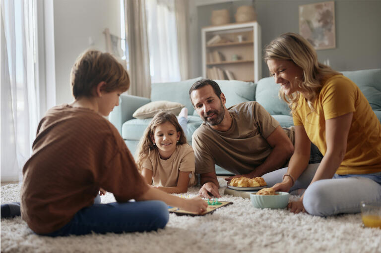 Family sits on the floor of their living room playing a game