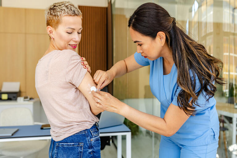 A young woman living with type 1 diabetes consults with a healthcare professional in a doctor's office. The woman receives monitoring equipment to track her blood sugar levels.