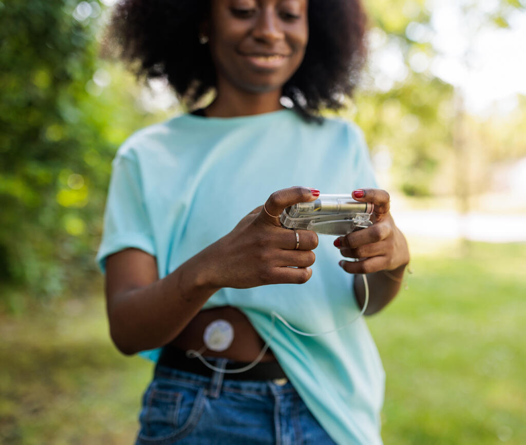 Young woman managing type 1 diabetes using technology for health monitoring, outdoors, combining health management with daily life, using insulin pump