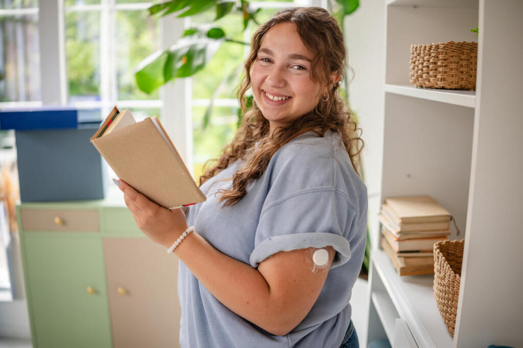 Young woman living with type 1 diabetes wears a continuous glucose monitor on her arm.