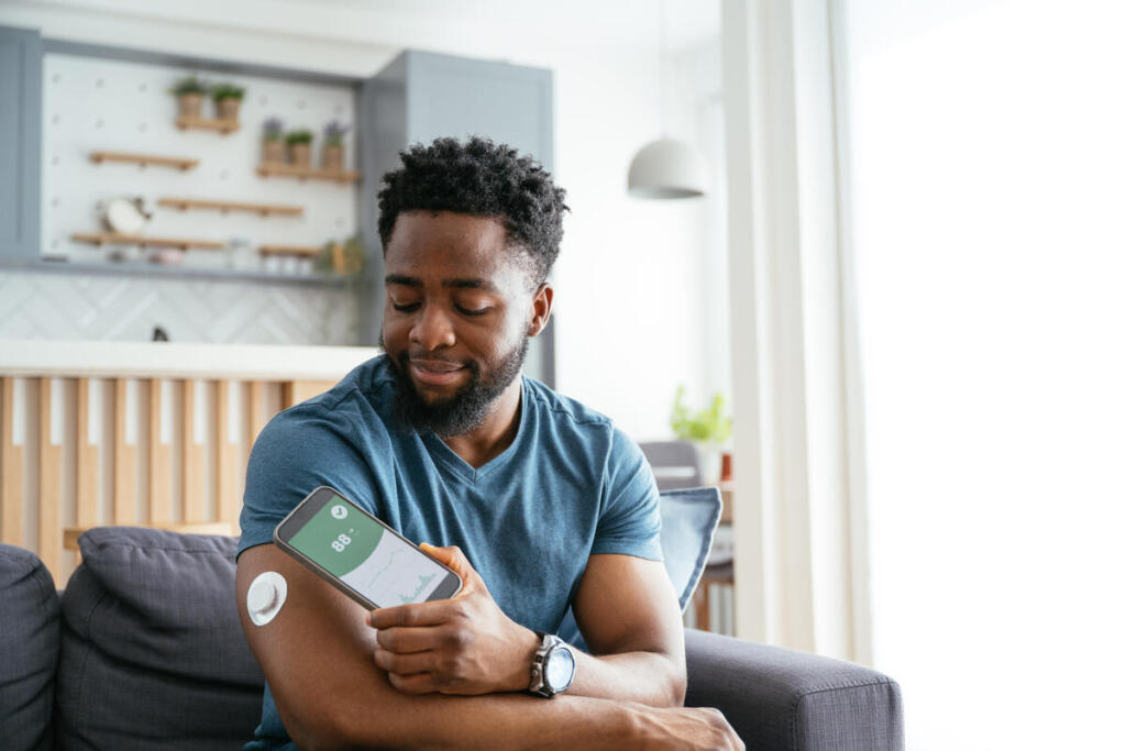 Adult male with type 1 diabetes checks his blood sugar using a continuous glucose monitor.