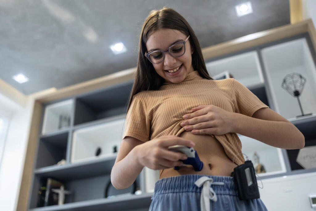 Teenager wears an automated insulin delivery system and applies her CGM