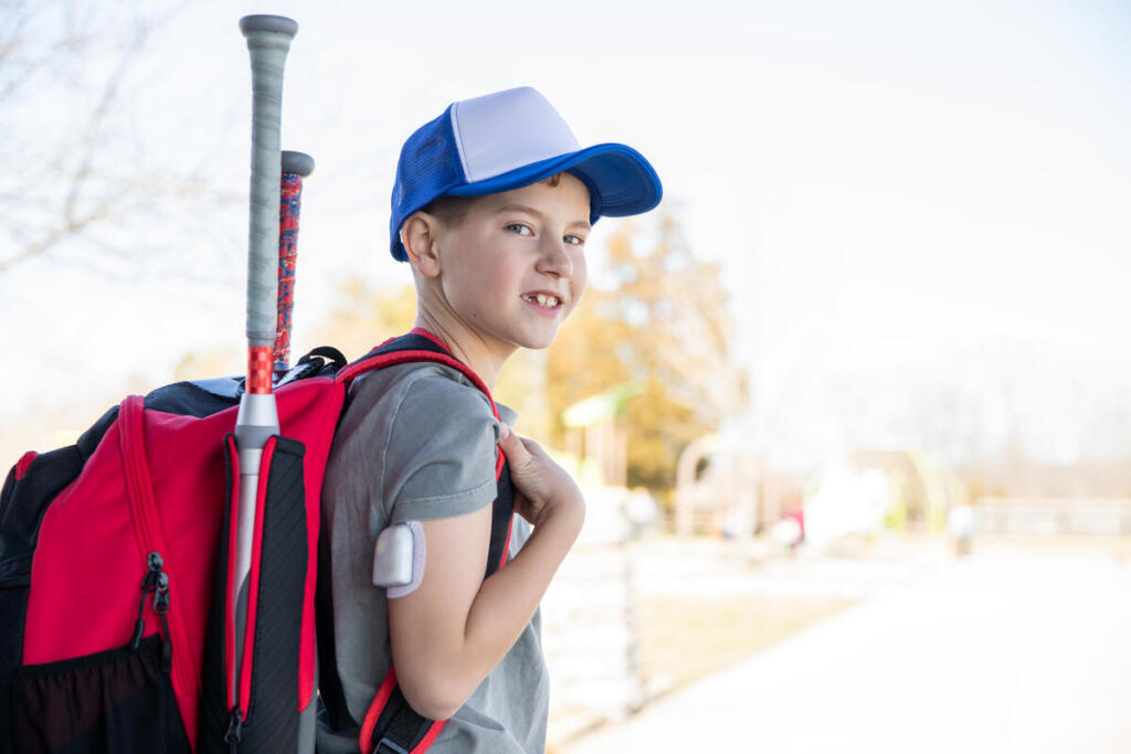Boy with type 1 diabetes wearing a backpack heads to school
