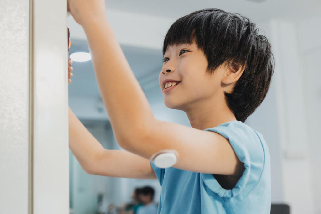 Young boy with type 1 diabetes (T1D) wears a continuous glucose monitor (CGM) on his arm.