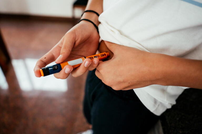 Young man injects insulin using an insulin pen