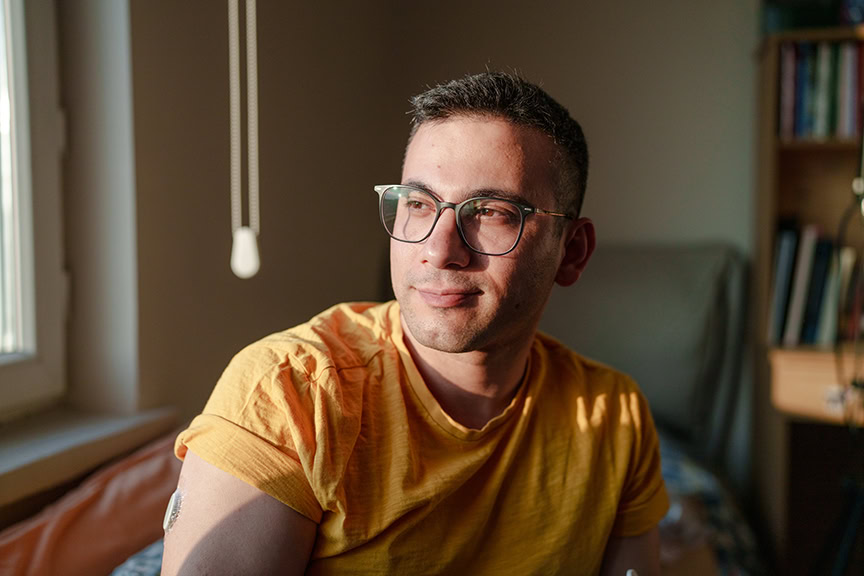 Young man with type 1 diabetes wearing a continuous glucose monitor