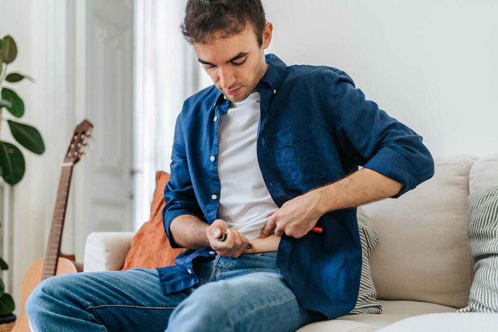 Adult man living with type 1 diabetes injects insulin using a smart insulin pen