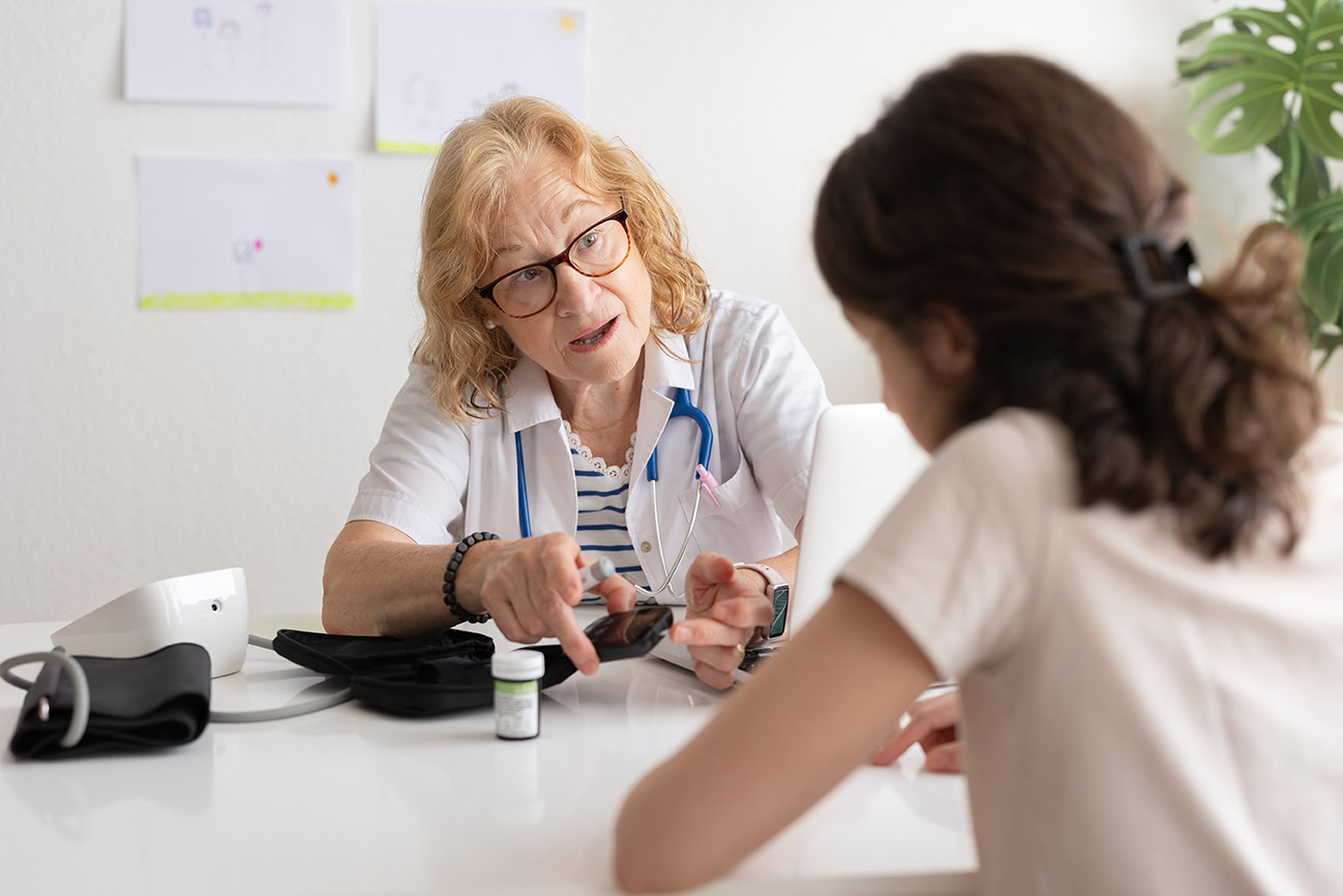 Female doctor shows patient with type 1 diabetes how to check her blood sugar using a glucometer