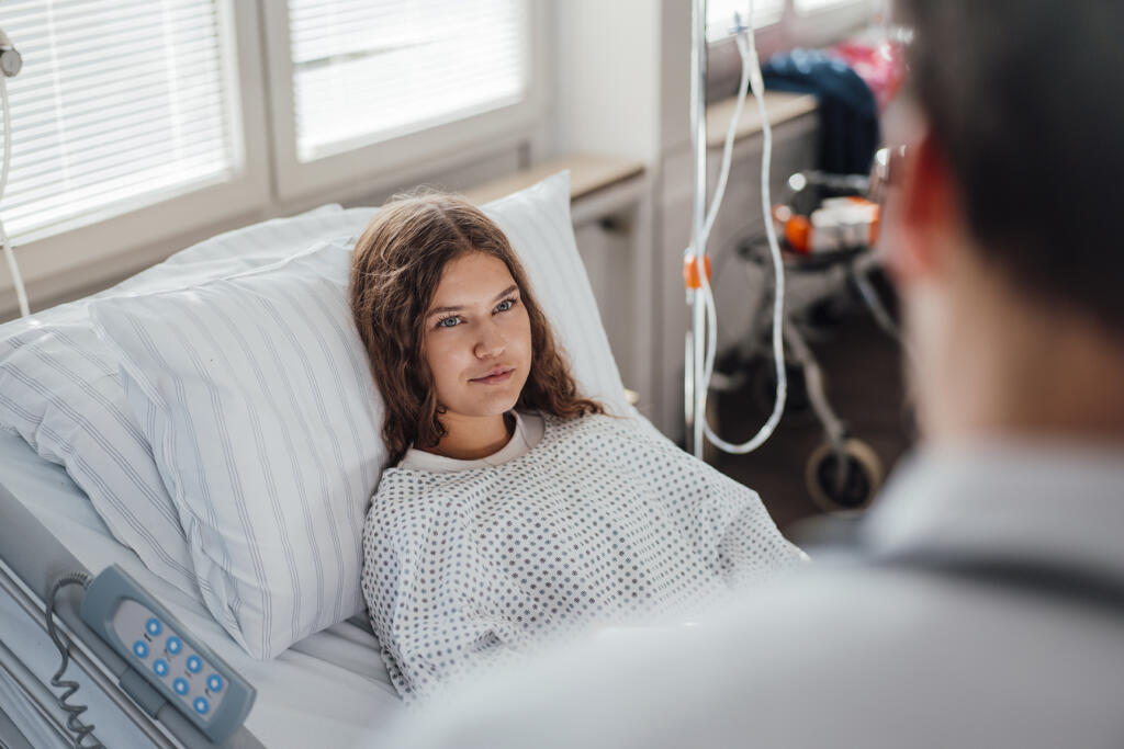 Doctor consulting patient in hospital bed during medical examination