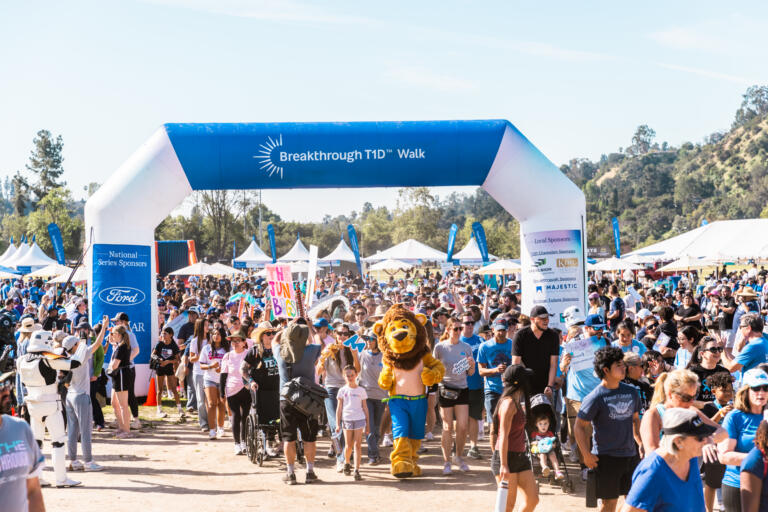 A massive crowd of people moves through an inflatable arch reading "Breakthrough T1D Walk."