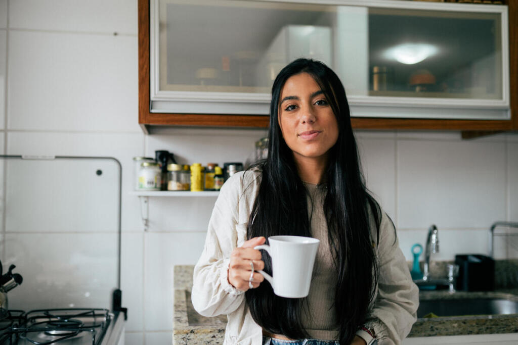 Young woman with type 1 diabetes drinks coffee in her kitchen