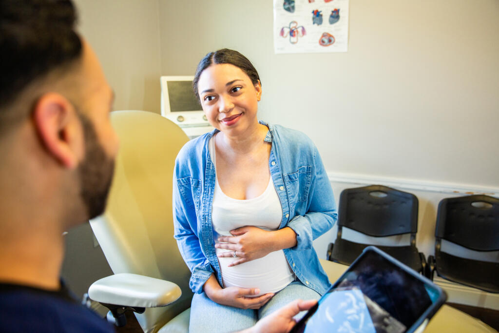 Young pregnant woman receiving prenatal care in an exam room