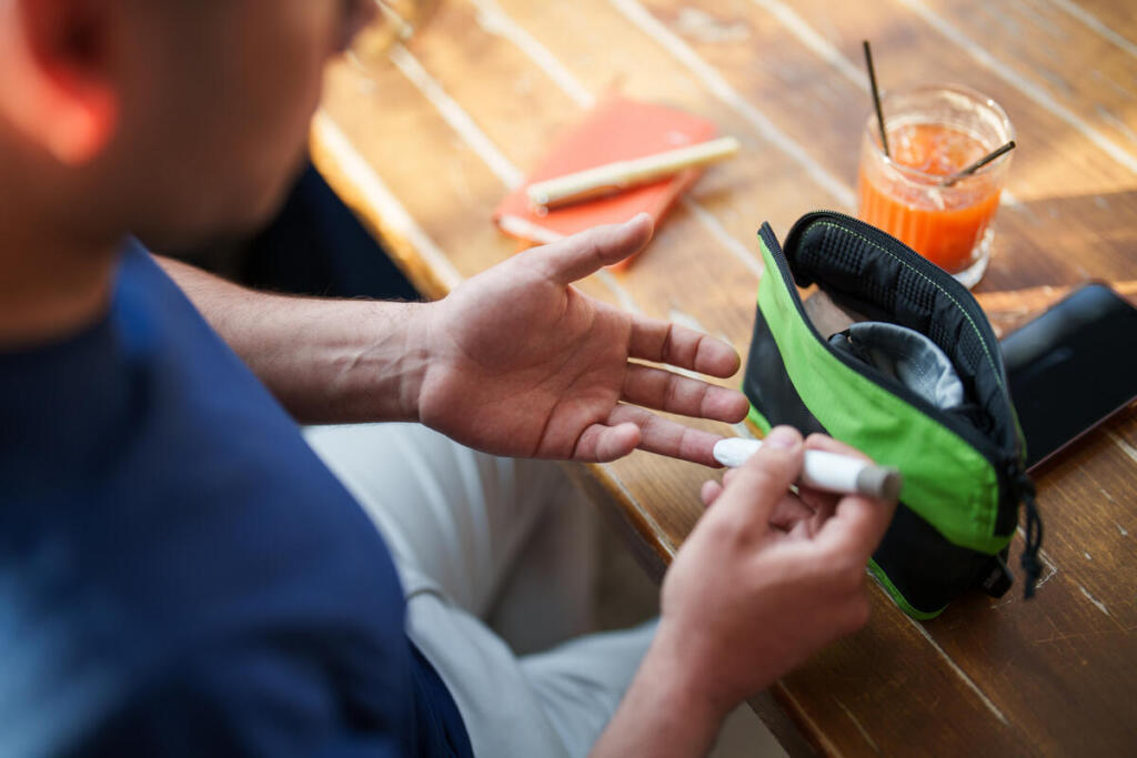 Man in a restaurant uses a glucometer to check his blood sugar before having a drink