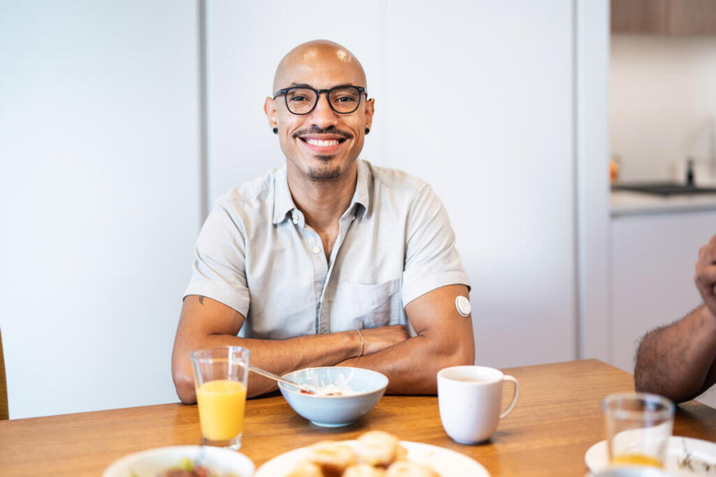 Young adult male with type 1 diabetes eating breakfast