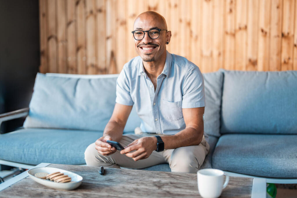 Adult male with type 1 diabetes sits on a couch to check his blood sugar