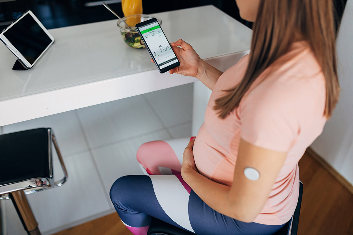Pregnant woman checks her blood sugar using a continuous glucose meter (CGM).