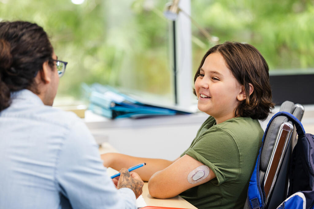 Child with type 1 diabetes talks to a teacher at school